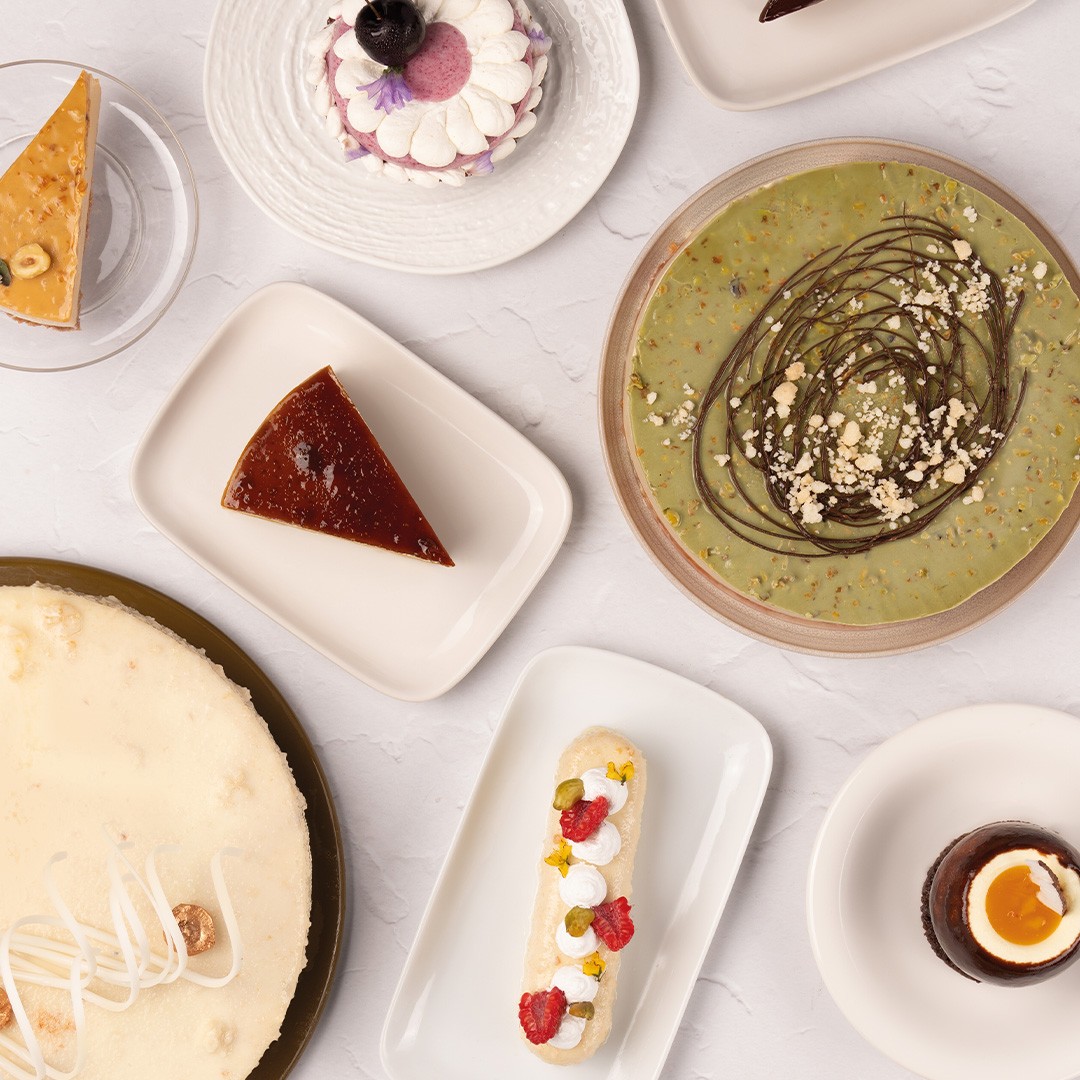 Άποψη από ψηλά με επιδόρπια: cheesecake, flan, ταρτάκι φιστικιού, eclair και ποτηράκια μους σοκολάτας